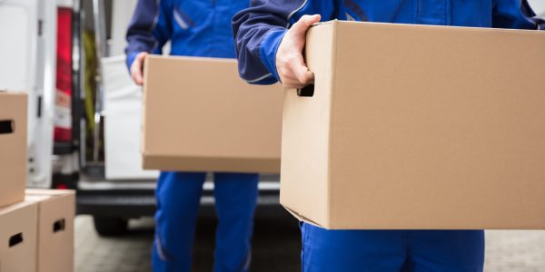 Close-up,Of,Two,Mover's,Hand,In,Uniform,Carrying,Cardboard,Box